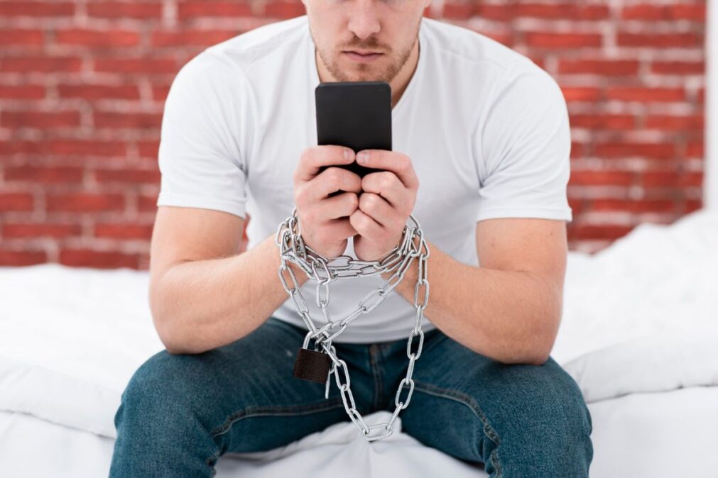 muž v řetězech s mobilem