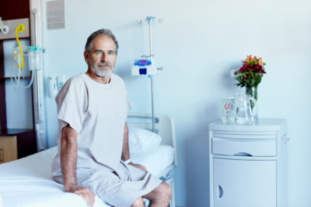 Muž sedí na nemocniční posteli