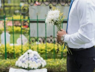 Muž s květinou na hřbitově