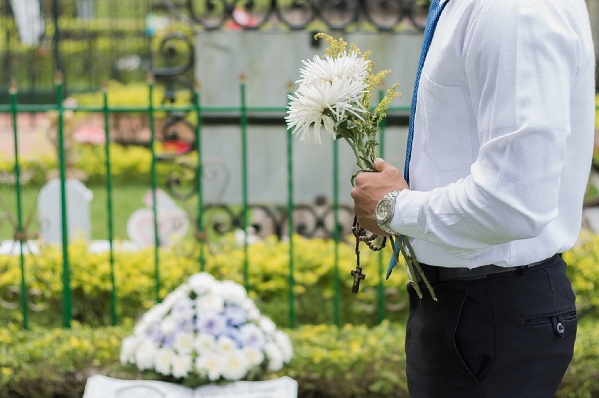 Muž s květinou na hřbitově