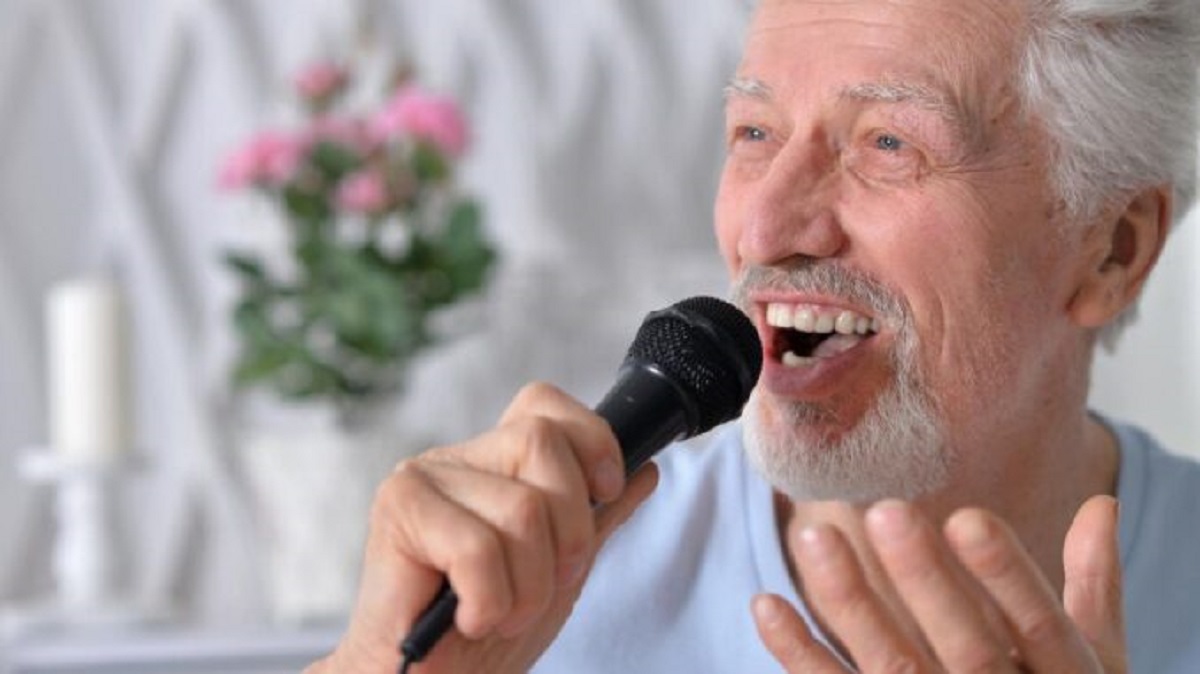 Starší muž zpívá do mikrofonu